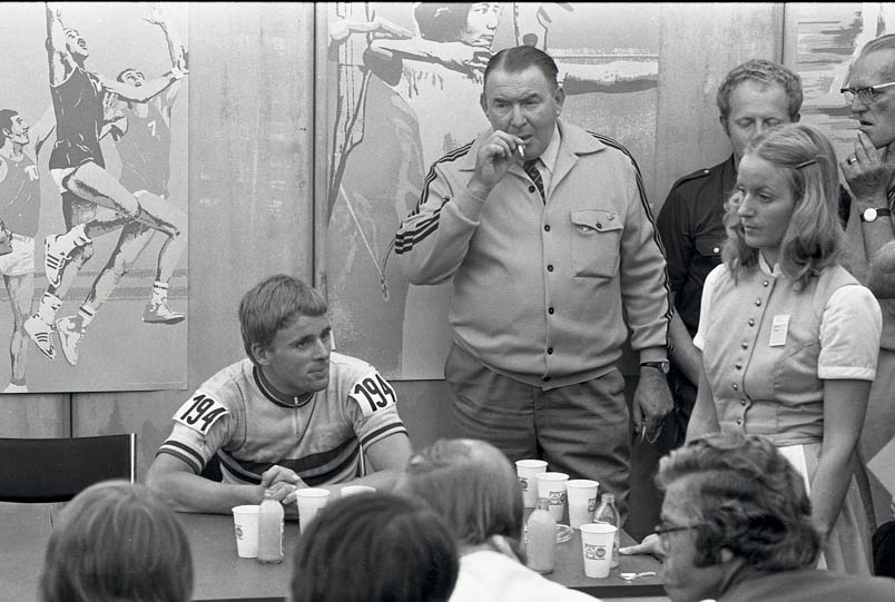 The Olympic champion is speaking to the international press. Behind Hennie Kuiper, Joop Middelink lights a cigarette. In his left hand, he holds Hennie's gold medal. Standing, on the right, are masseur Jan Kuiper and Dutch mechanic Jan Spenkelink. Bottom right: Frans van der Mespel from the Eindhovens Dagblad